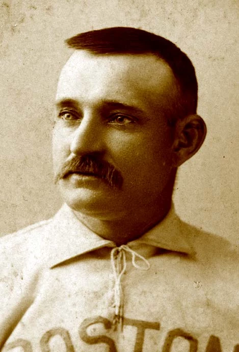 light-skinned portrait of a man with dark hair and a dark mustache. He is wearing his baseball uniform, which is cut off along the bottom of the photo, but the word