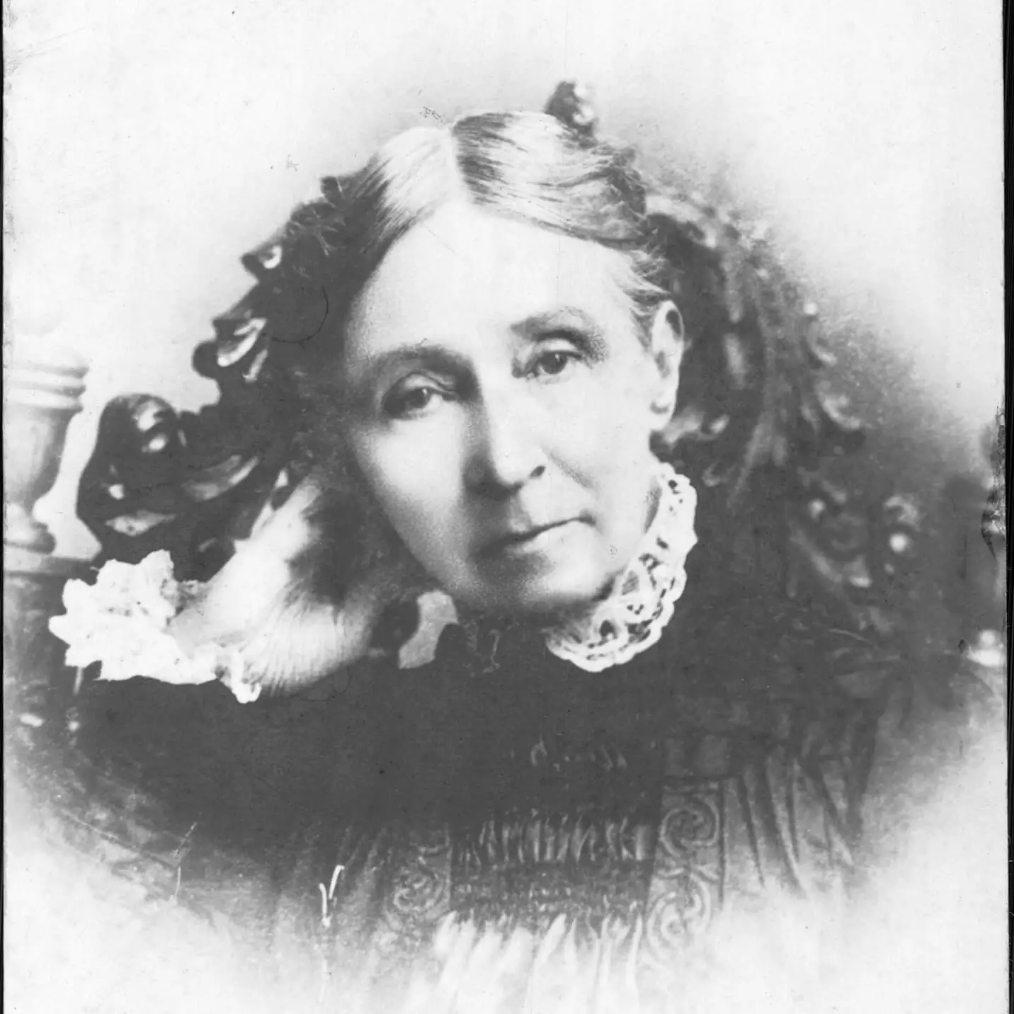 Black and white portrait of a pleasant looking older white woman in collared dress, sitting in an ornate chair.