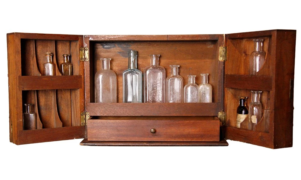 Dark wooden medicine box with doors that open and hold multicolored glass medicine bottles on their shelves.