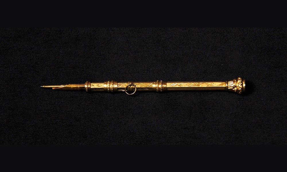 Golden ornate pen/pencil photographed on a dark background