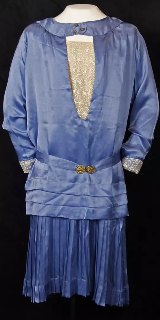 Periwnkle blue silk long-sleeved blouse with a v-neck cutout featuring a gold pattern, over blue silk pleated skirt