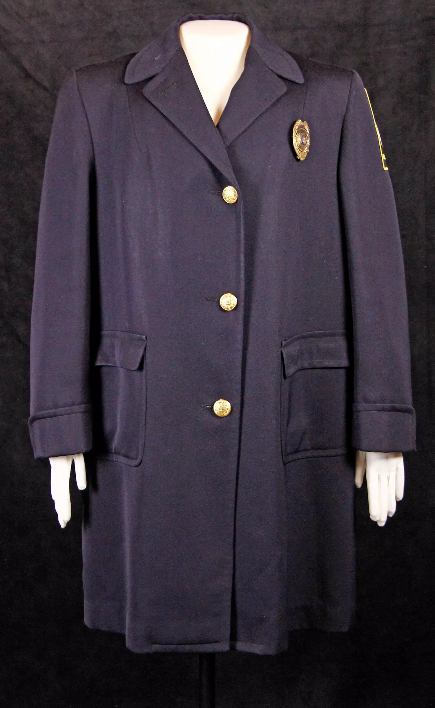 Dark blue long police coat with badge on upper left.