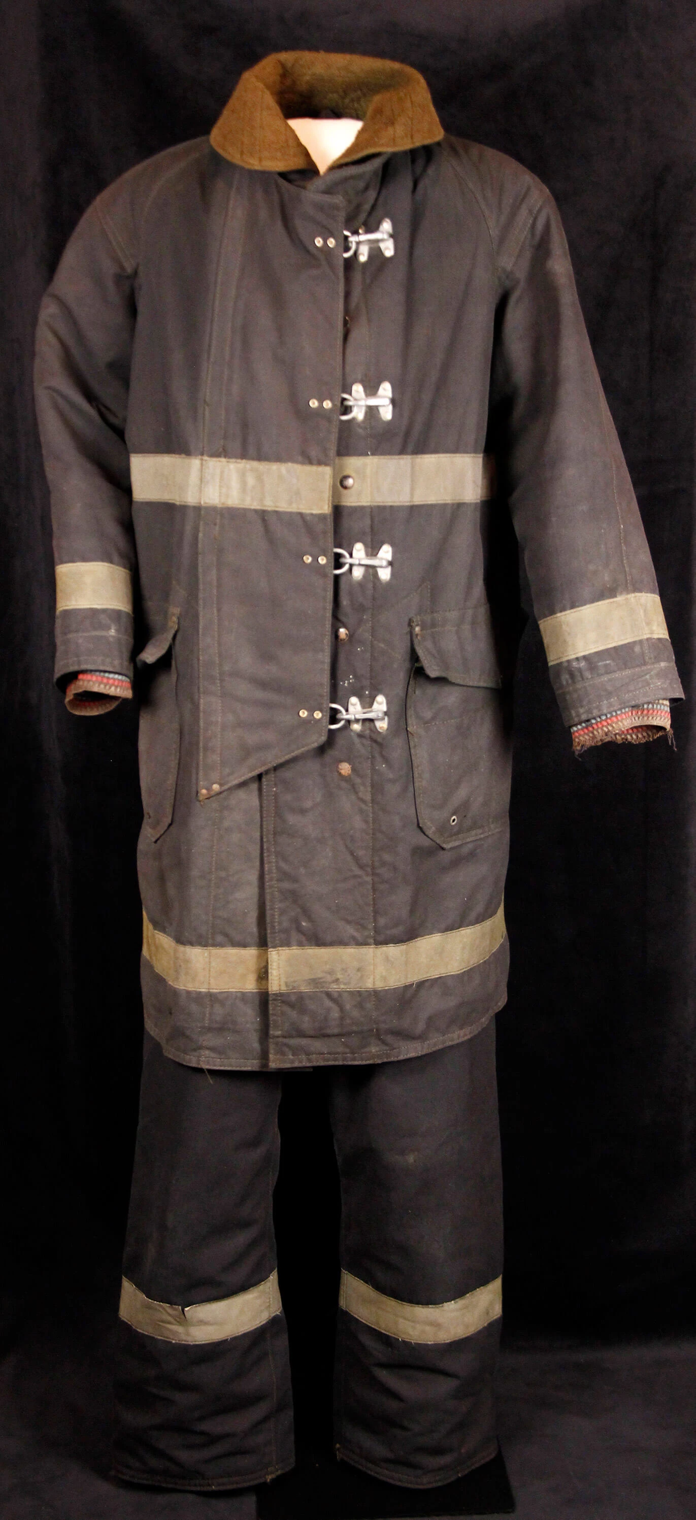 Black uniform with yellow stripe. Coat is long sleeved and goes to the middle thigh, and has large metal buckles to close it.