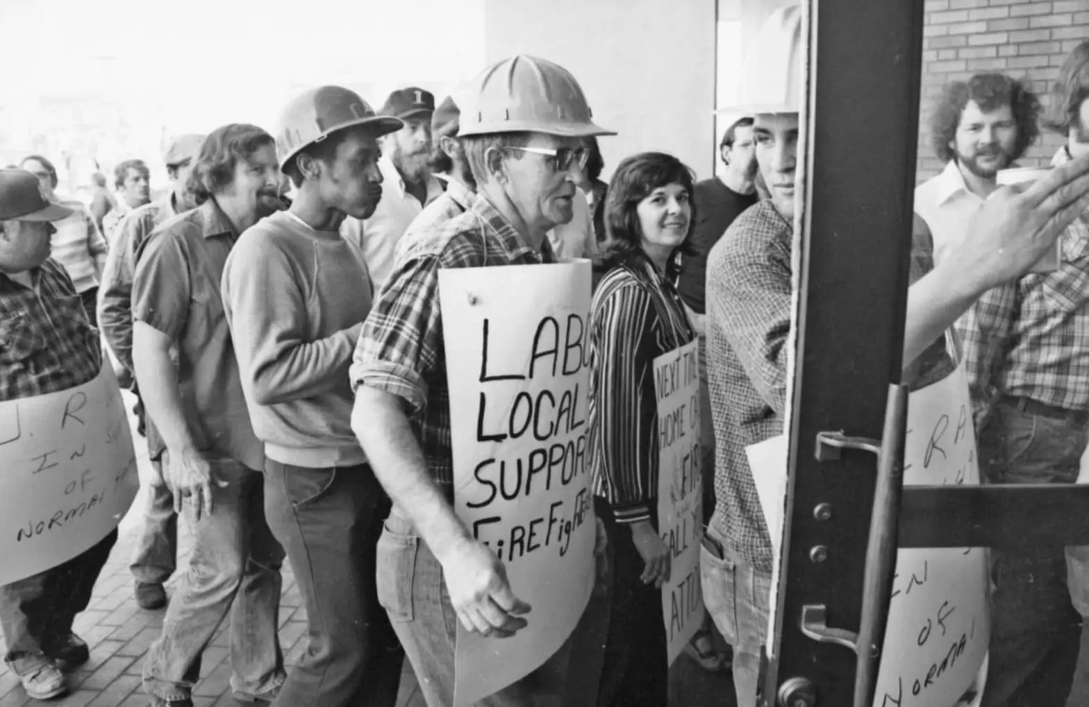 Photo of a group of men and women, some in hard hats, carrying signs in support of the union.