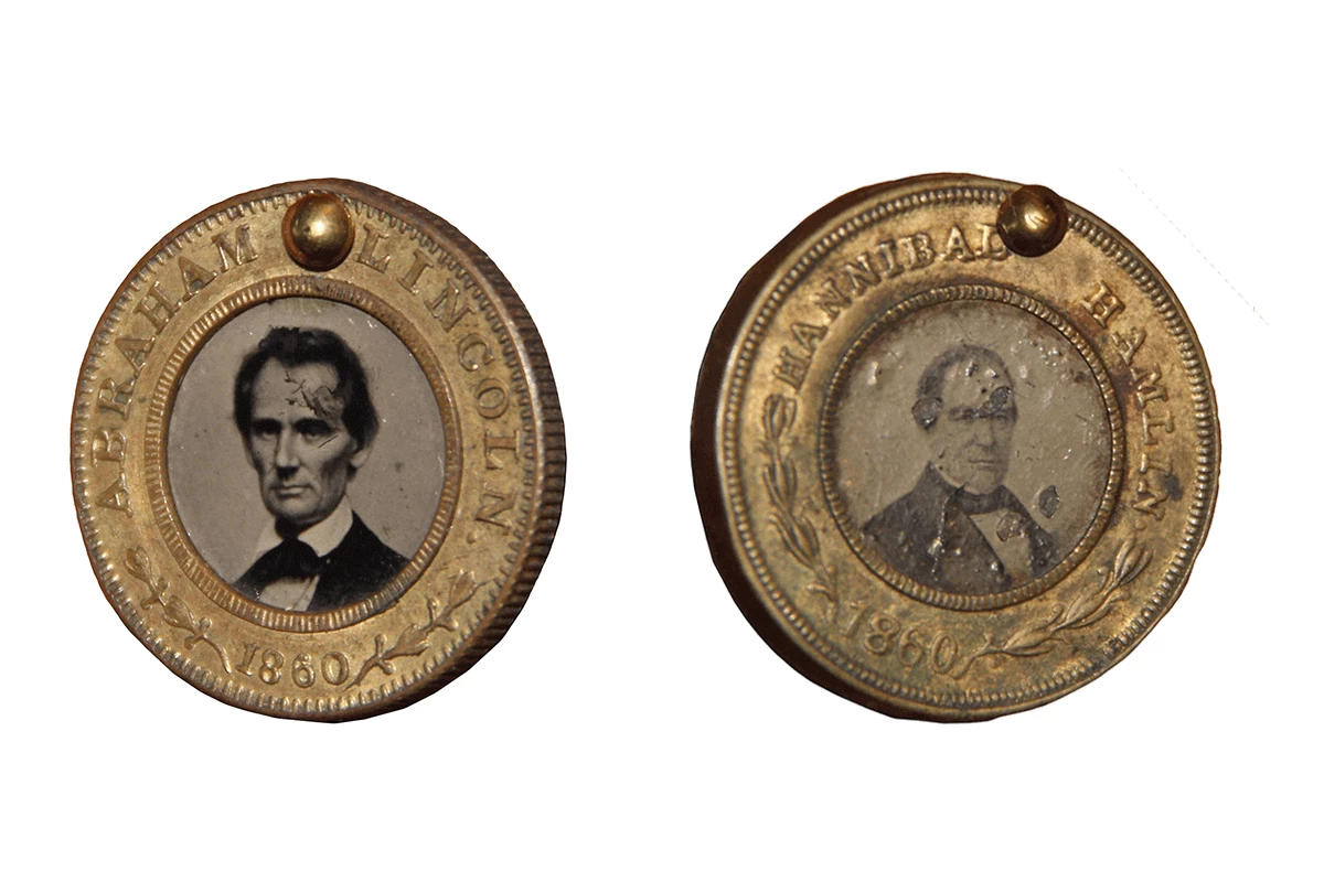 Two small gold-colored tokens, with black and white photos of Lincoln and Hamlin in the center.