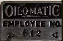 Metal badge that says Oil-O-Matic Employee No. 612