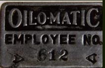 Metal badge that says Oil-O-Matic Employee No. 612