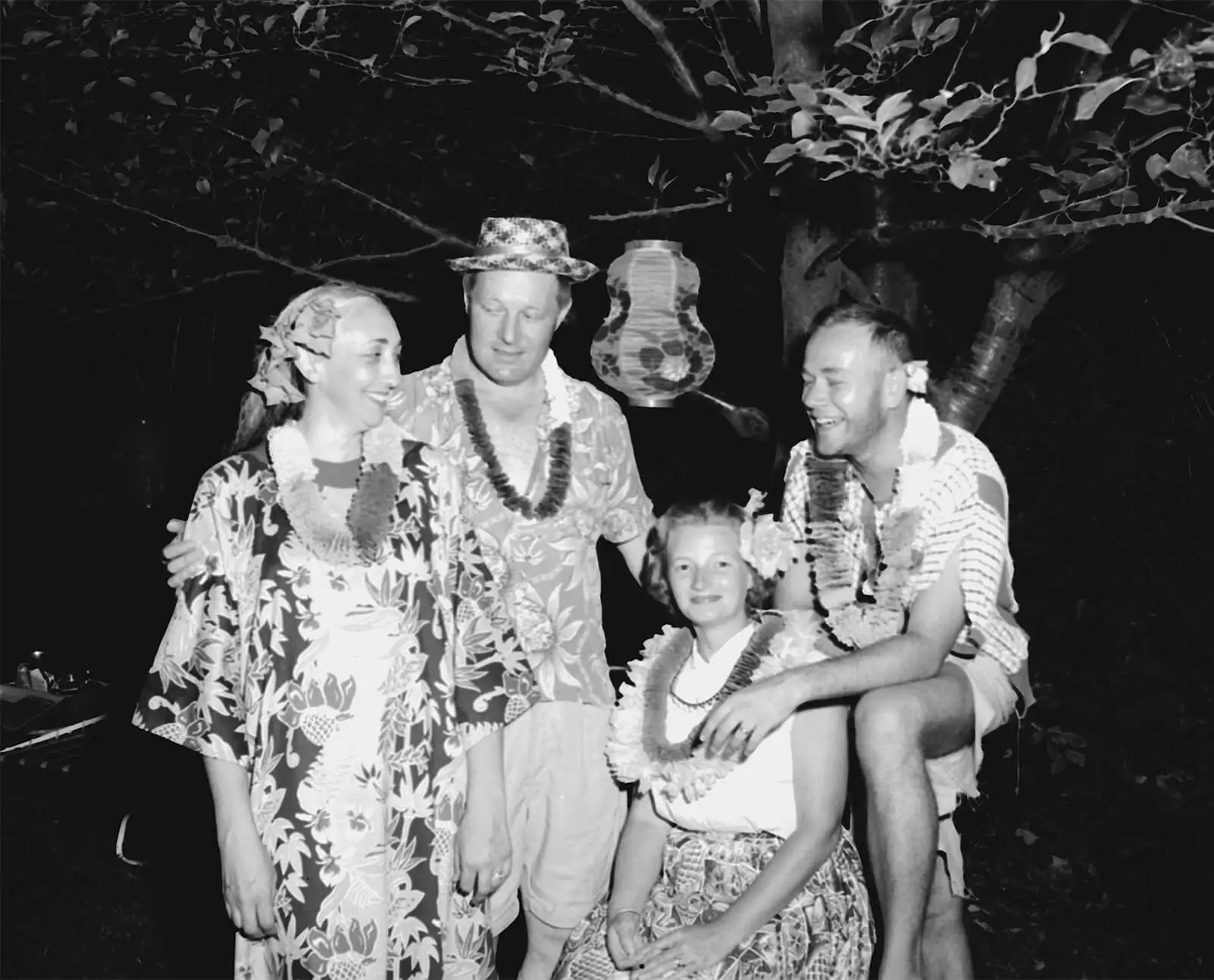 Two men and two women dressed in floral shirts and wearing leis.
