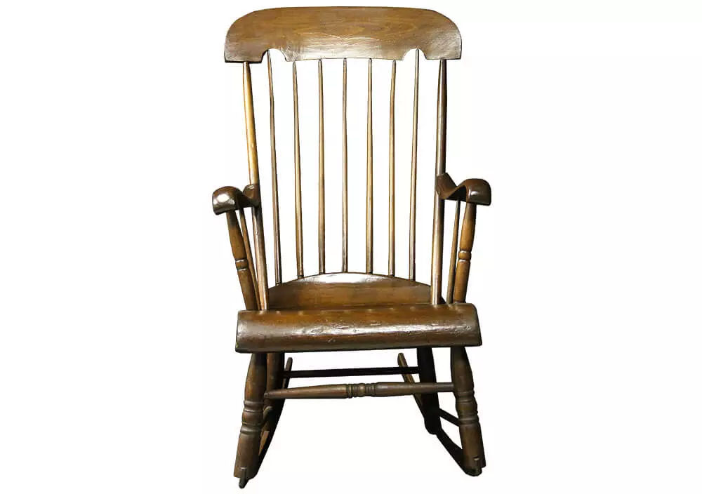 Photo of an oak-colored wooden rocking chair. The back of the chair are vertical spindles.