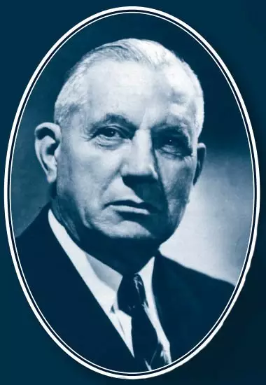 Portrait of light-skinned older man with his light colored hair combed backwards. He is looking to the left of the camera with a serious face, wearing a suit and tie.