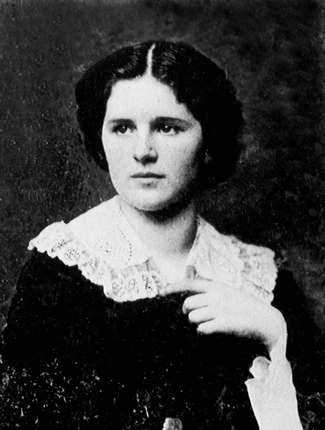 Black and white photo of a young woman in a dark dress with a lace collar, dark hair with a middle part.