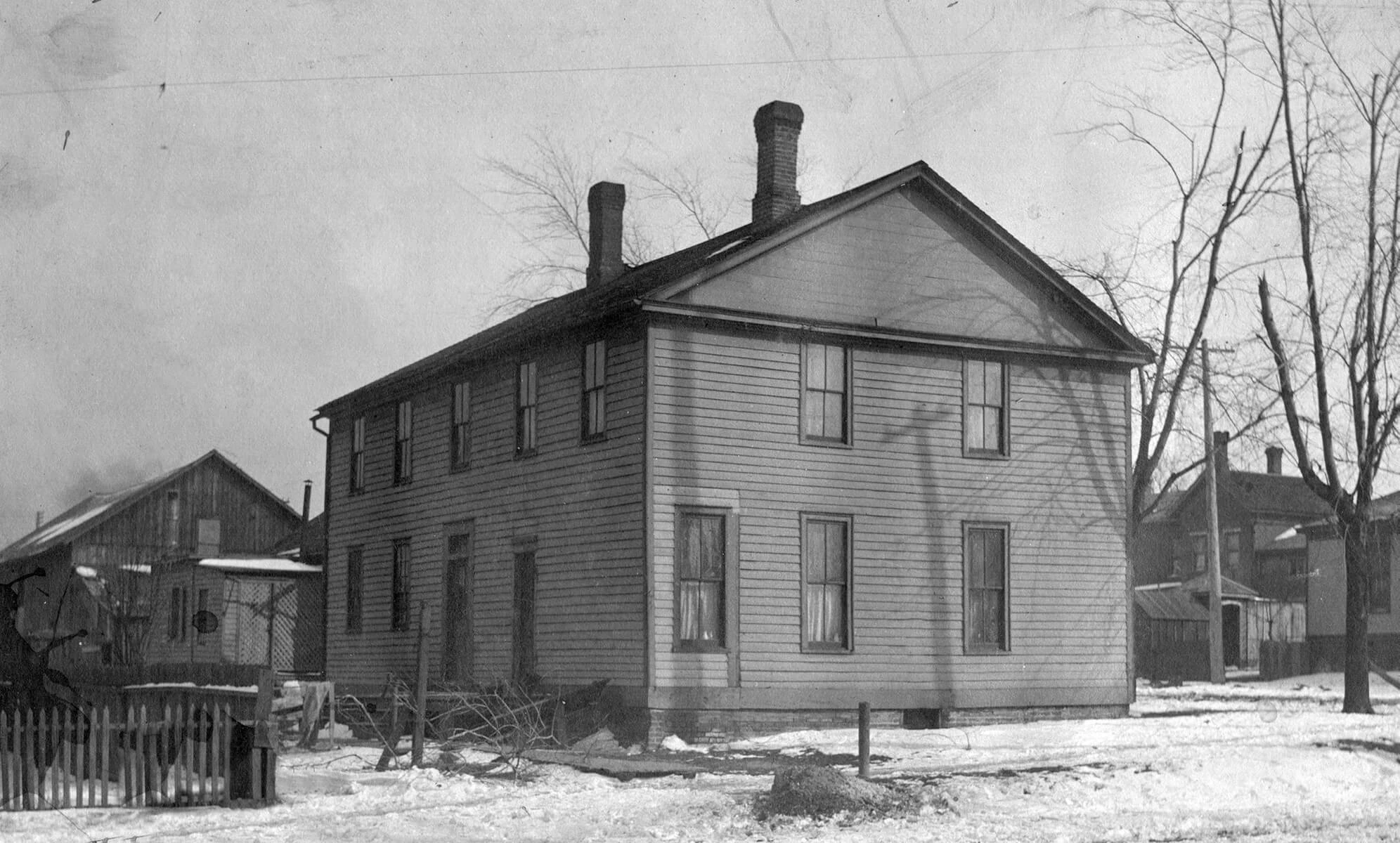 A two story wooden building with many windows and two chimneys coming out the top.