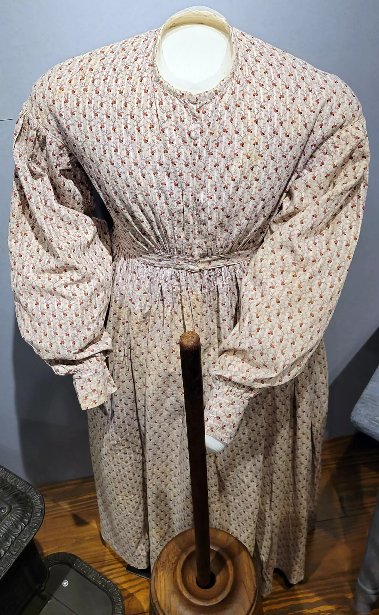 A mostly white dress with a simple pattern. It is long sleeved with a belt at the waist.