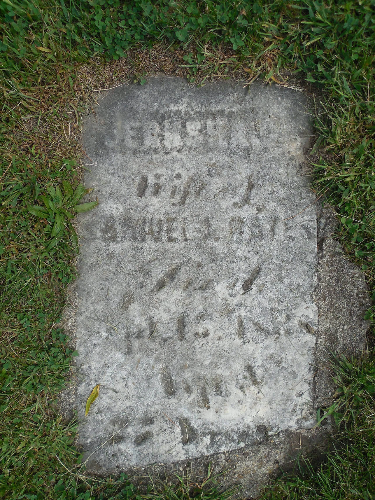 Flat gravestone surrounded by mowed grass.