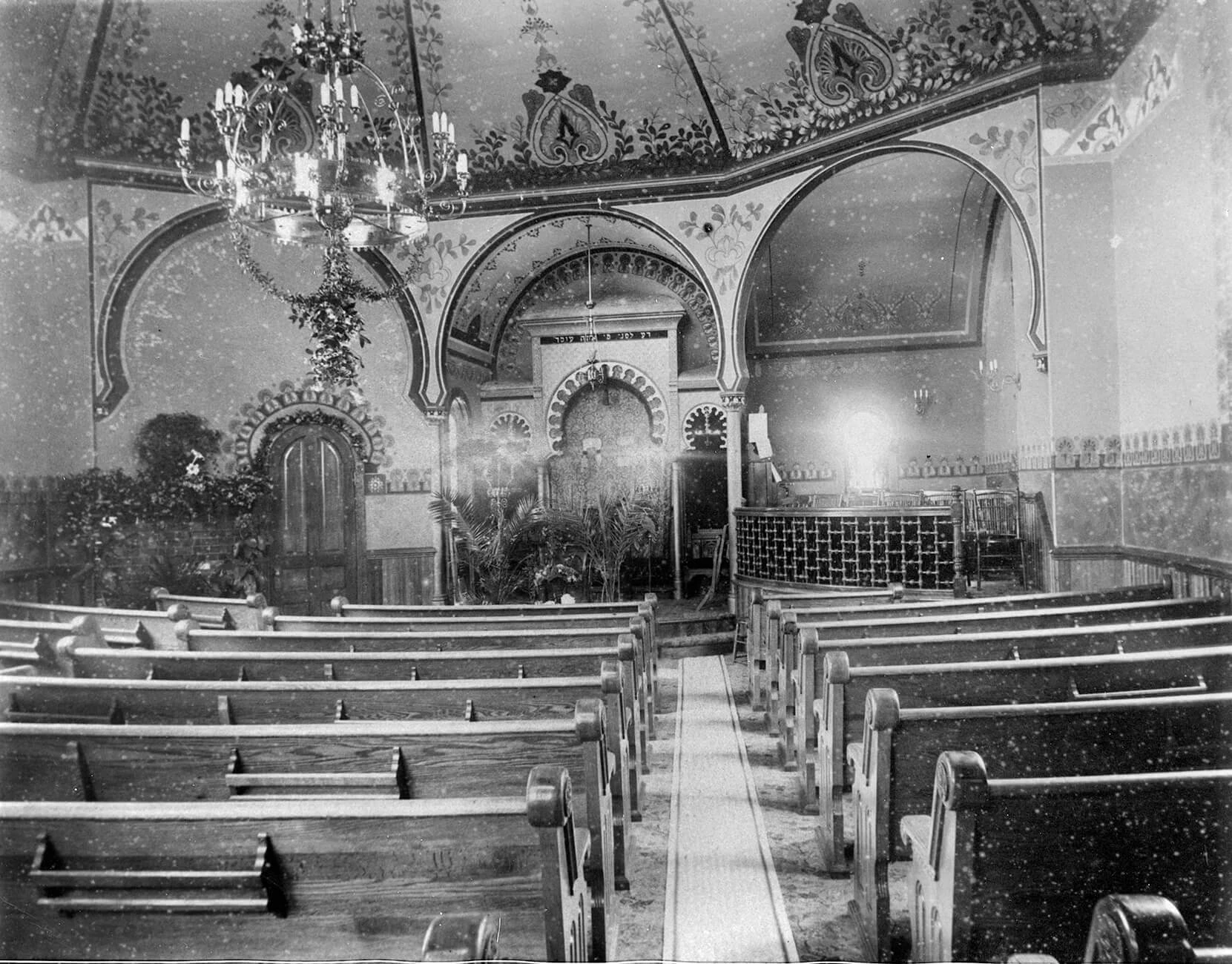 wooden pews face an arched room with ornate chandelier