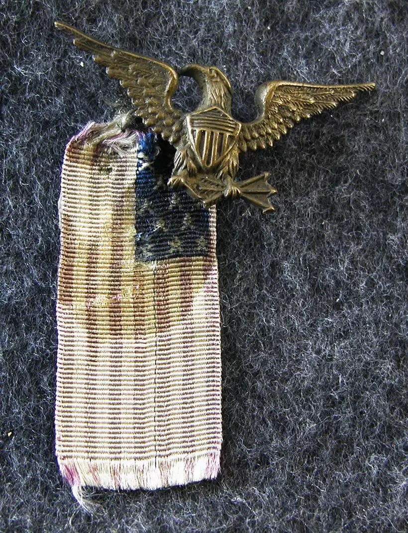 Small cloth American flag ribbon and brass Eagle with shield.