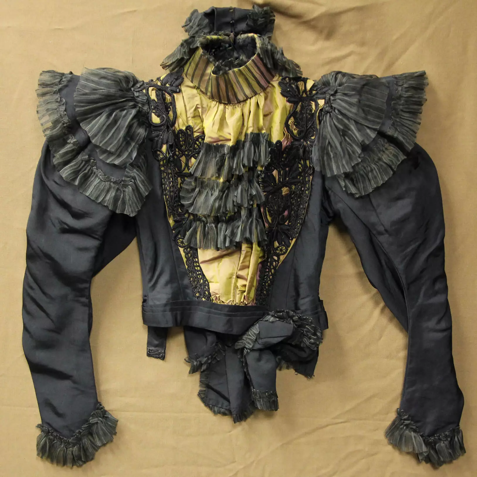 black silk bodice with beige or gold layer underneath black ruffles in the front.