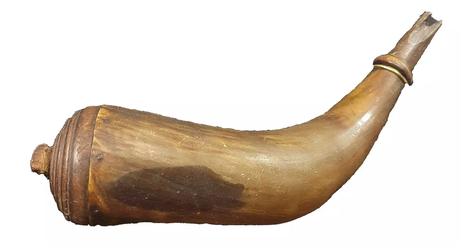 12 inch long powder horn made from bovine horn. It has a rounded wooden plug in the large end, secured with 5 brass tacks. The small end of the horn has been carved to form conical section at tip.