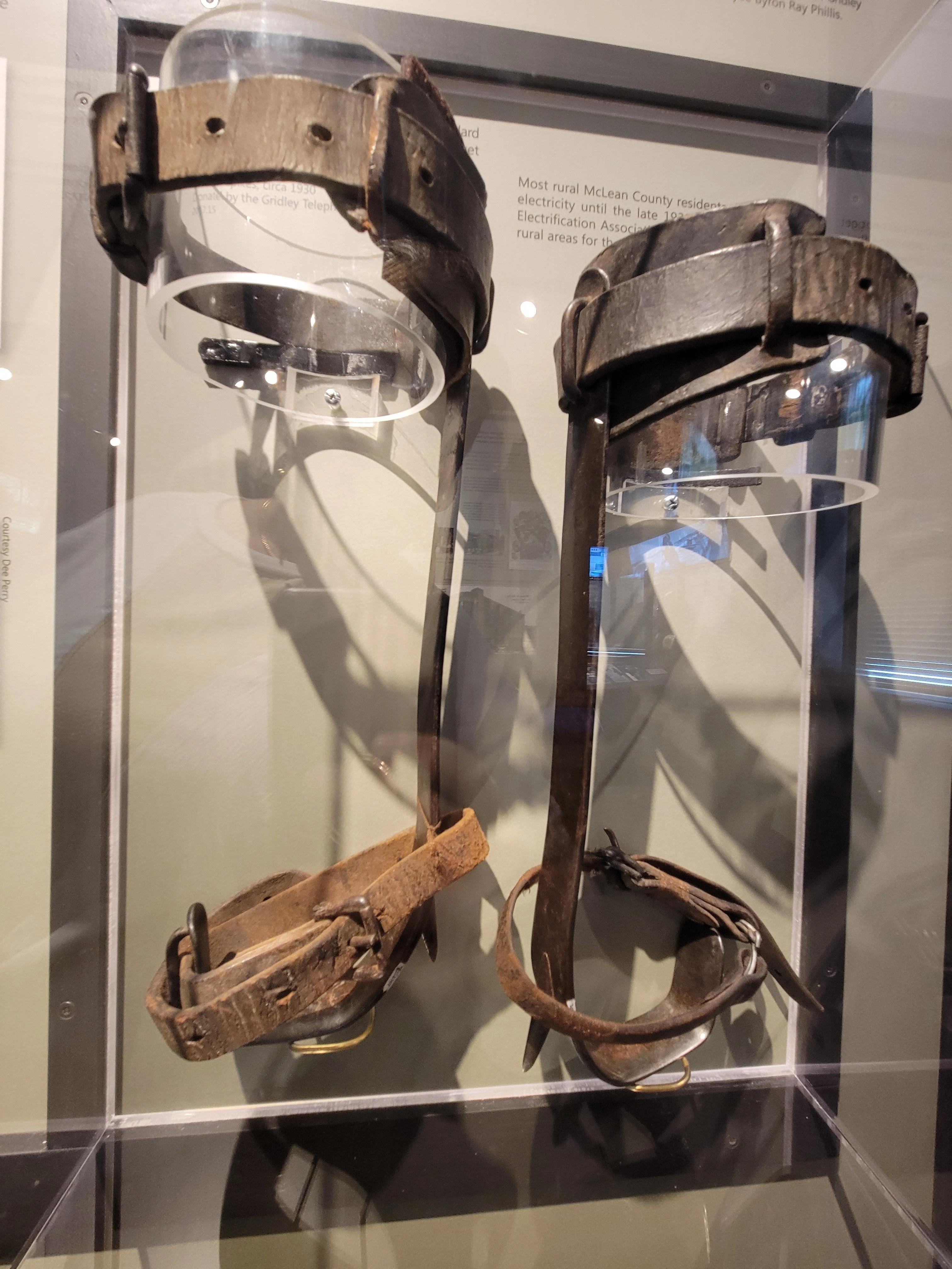 Adjustable leather straps that go around the legs and feet. A metal rod goes down the side of the leg and under their boot, with a point that protrudes on the bottom, allowing the worker to securely climb up a pole.